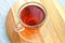 Glass cup, mug of red colored, hot Rooibos tea or red bush tea on a wooden plate, aromatic drink, beverage, tonic, stimulant