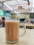 Glass cup of tea with milk locally known as Teh Tarik on the table.