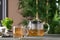 Glass cup and teapot of delicious chamomile drink on wooden table