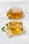 Glass cup and teapot with jasmine green tea on a white background, vertical top view