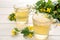 Glass cups of aromatic celandine tea and flowers on white wooden table
