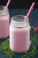 Glass cups with delicious strawberry milkshake on a black table