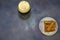 A glass of dark beer with white foam and a plate with wheat croutons on a gray background