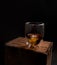 Glass of dark liquor on wood box