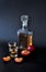 A glass decanter and two glasses of plum liqueur and ripe sliced fruits on a black background