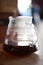 Glass drip pot with black coffee on table, closeup with blurred background