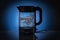 Glass electric kettle filled with water while boiling. On a blue conceptual background.