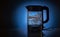 Glass electric kettle filled with water while boiling. On a blue conceptual background.