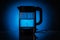 Glass electric kettle filled with water while boiling. On a blue conceptual background.