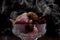 Glass filled with brown, pink and red potpourri with smoke with black background. Rembrandt lighting inspired