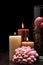 Glass filled with brown, pink and red potpourri with three lit candles on wooden table with black background. Rembrandt lighting