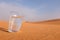 A glass filled with water in a hot desert landscape showing drink water regularly and summer heat concept