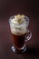 Glass of frappucino with whipped cream and almonds shaving on elegant dark brown background