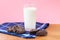 Glass of fresh milk with a pile of crunchy baked chocolate sugar cookies on wooden table with dark blue dinner napkin on pink back