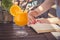 Glass of fresh orange juice on table and female reading a book i