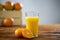 Glass of fresh orange juice on wooden table with grapefruits in background