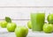 Glass of fresh organic apple juice with granny smith and british bramley apples in box on wooden background with sun light