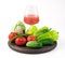 A glass of freshly squeezed vegetable juice and a large selection of fresh vegetables on a round tray.