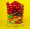 A glass full of colorful candies with a yellow background 3
