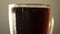 Glass full dark craft beer closeup rotate with drop of condensation cold drink