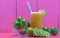 Glass of Galician lemon juice Citrus auranti and halved fruits on pink background