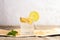 Glass with ginger water on piece of bark on burlap on white textured background.