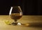 Glass glass with cognac on a wooden table, lemon slice, dark background. Free space for text on the side