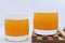 Glass glasses with orange juice on a wooden stand. A soft drink in a glass on a white background