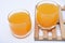 Glass glasses with orange juice on a wooden stand. A soft drink in a glass on a white background