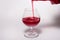 Glass goblet with red drink on a white background. With a splash of liquid from the bottle.