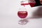 Glass goblet with red drink on a white background. With a splash of liquid from the bottle.