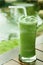 Glass of green tea frappe on wooden table in garden