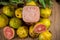 Glass of guava juice Psidium guajava L. between leaves and fruits on a neutral background