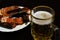 Glass half-liter mug filled with beer on the blurred background of a snack of dried smoked fish on the table