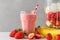 Glass of healthy smoothie or milkshake made of strawberry, banana, almond milk with blender and straw