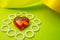 Glass heart on a green substrate with a yellow ribbon, love