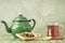 Glass of herbal tea and enamel teapot on table