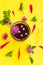 Glass with hibiscus or karkade tea with different wildflowers on yellow background. Top view