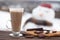 Glass of hot chocolate or cocoa with cookies and chunks of dark chocolate on wooden table.