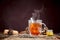 Glass of hot golden tea with spoon on table of wood