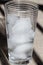 Glass of ice melting, light background