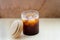 a glass of iced americano. glass of cold coffee with steam. new generation coffee shops and cold brew. on white wooden line