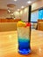 Glass of iced blue lime soda with straw on wooden table