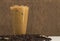 A glass of iced coffee with coffee beans on table and brown wooden background