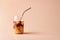 Glass of iced coffee in tall glass with golden straw with cream on pastel background for your design. Food concept in