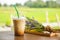 glass of iced coffee on wooden balcony with green nature background