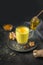 Glass of Indian golden turmeric latte milk with curcuma root, powder on black. Vertical shot