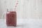 Glass jar with berry smoothie made of banana, black currant, coconut milk on a white wooden background, side view.