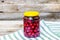 Glass jar with canned cherries fruits. Preserved fruits concept, canned fruits compote isolated in a rustic composition