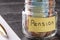 Glass jar with coins and euro notes with the words PENSION. Pen and blank note paper